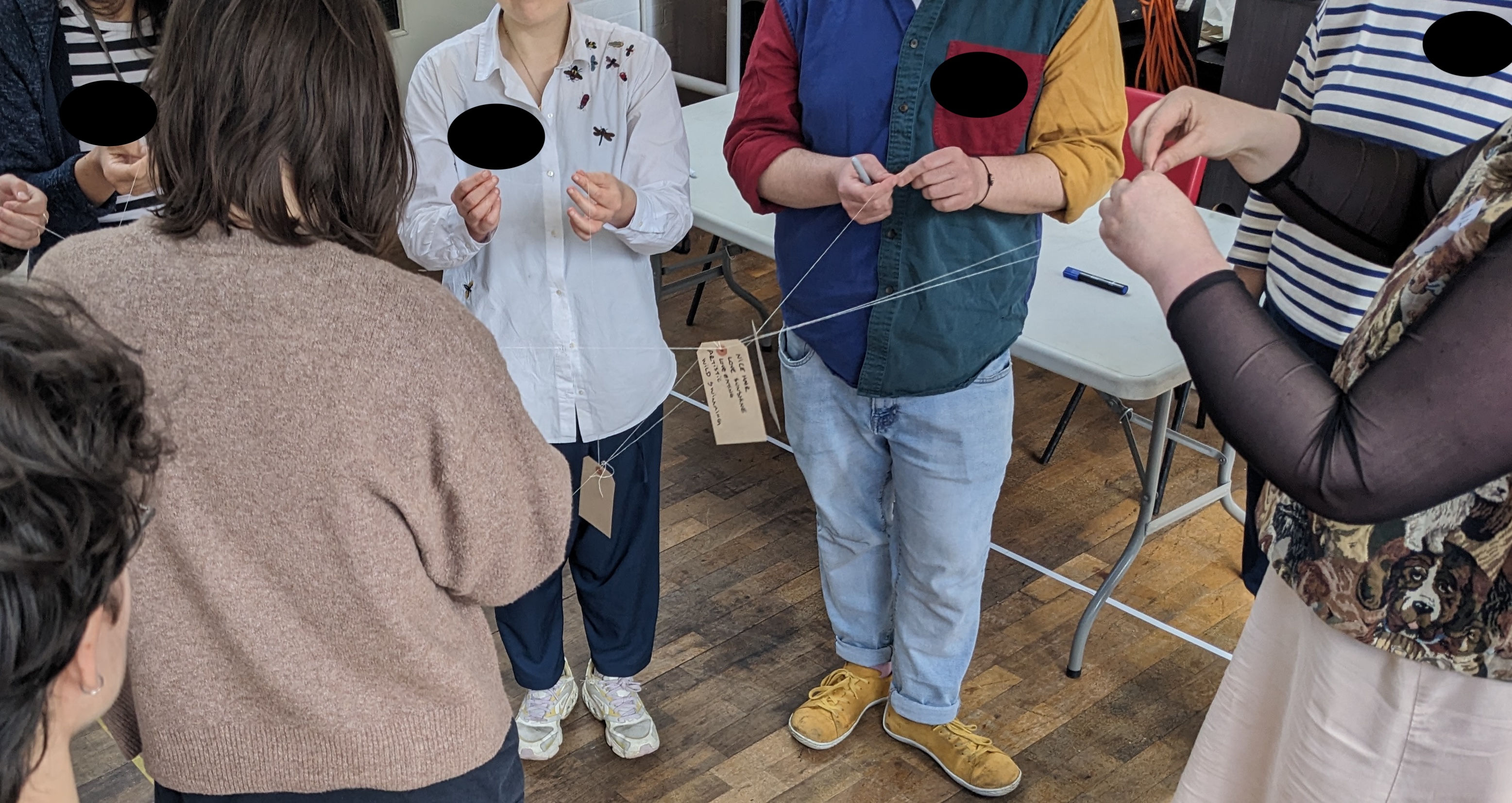 people standing in a circle with a luggage tag on a string connecting them all